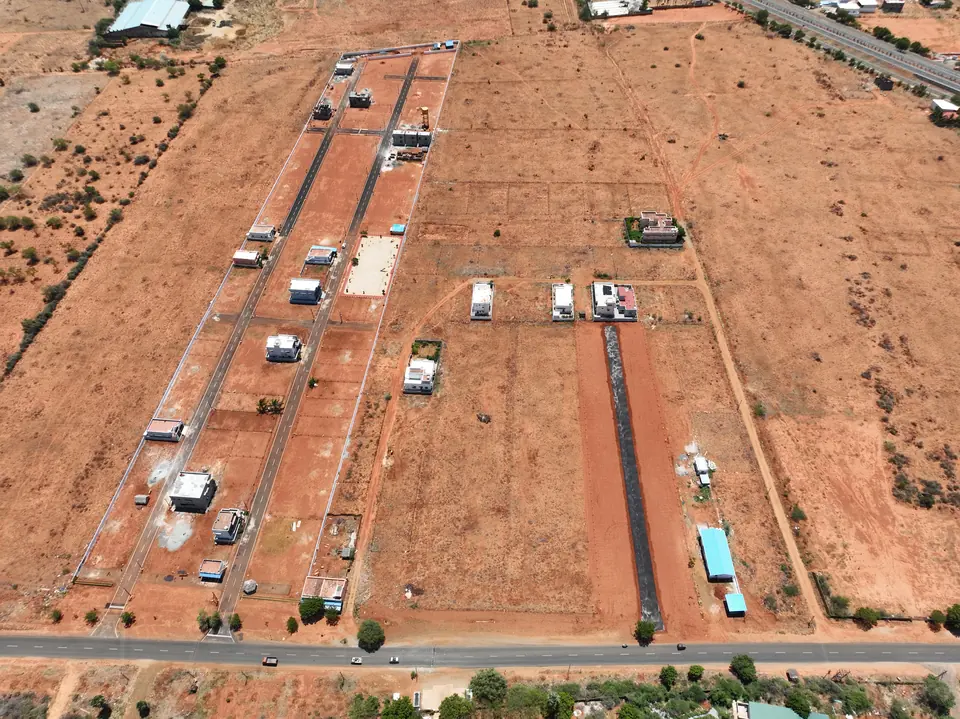 Aerial view of the development from the opposite side, with the highway running along one edge